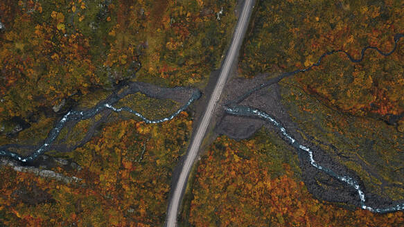 Luftaufnahme eines gewundenen Flusses, der eine herbstlich gefärbte Landschaft durchquert, mit einer Straße, die die Szene halbiert. - ADSF53365
