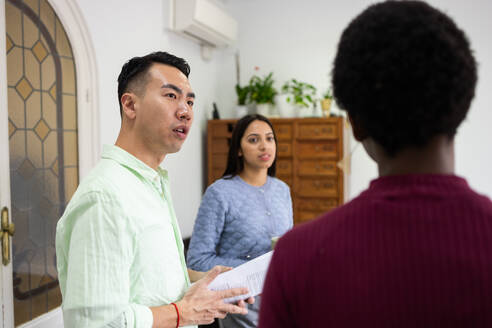 Three diverse colleagues in a professional setting reviewing a document together, focusing on teamwork and collaboration. - ADSF53601