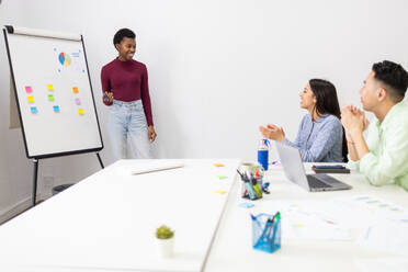 Businesswoman leads a team meeting with colorful sticky notes and charts. - ADSF53615