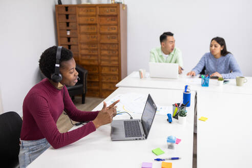 Diverse team in a modern office with one member leading a virtual meeting. - ADSF53633