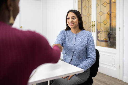 A professional young woman smiles confidently during a job interview, making a great first impression. - ADSF53647