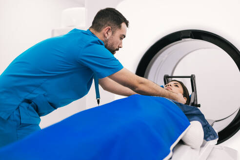 Male technician assisting a female patient before a computed tomography scan in a modern clinical setting. - ADSF53676