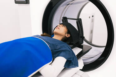 A female patient lies in a medical scanner during a magnetic resonance imaging (MRI) procedure. - ADSF53678