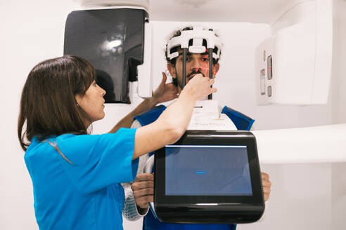 A dental healthcare worker is using a 3D dental scanner to examine a patient's teeth, ensuring precision in diagnosis. - ADSF53685