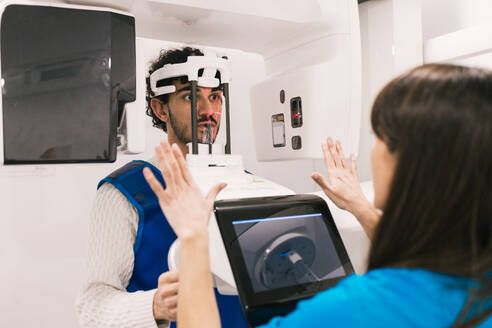 A patient undergoes a CT scan in a dental clinic with a technician guiding the process. - ADSF53686