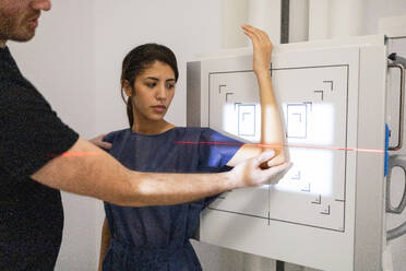 A technician assists a patient with positioning her wrist for a digital x-ray scan in a modern medical facility. - ADSF53696