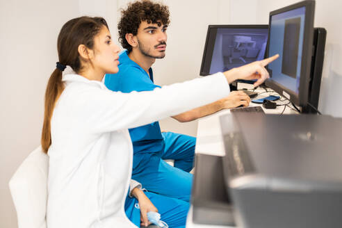 Two healthcare workers are intently looking at a monitor, discussing medical data in a clinical setting. - ADSF53700