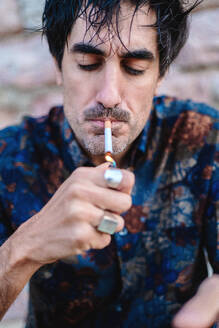 Close-up shot of a man lighting a cigarette, focusing on the lit match and his act of smoking - ADSF53832