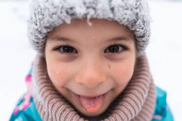 Close-up of a joyful child with a snowy hat smiling on a winter day - ADSF53895