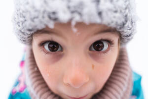 Close-up of a child's eyes looking up, wearing a woolen hat in a snowy setting - ADSF53897