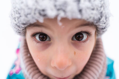 Close-up of a child's eyes looking up, wearing a woolen hat in a snowy setting - ADSF53897