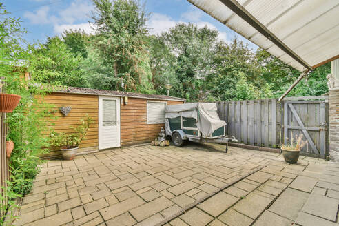 A cozy suburban backyard featuring a garden shed, a covered trailer, and lush greenery. - ADSF53980