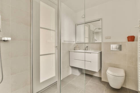 A contemporary bathroom featuring a glass shower, sleek sink vanity, and wall-mounted toilet in a bright and neutral color scheme. - ADSF53993