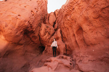 A traveler stands amidst the vibrant red rock formations of Los Colorados in northern Argentina, showcasing the natural beauty of this desert landscape. - ADSF54013