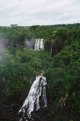 An awe-inspiring view of the Iguazu Waterfalls in Southern Brazil, framed by vibrant, dense jungle under an overcast sky. - ADSF54021