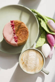 Cup of coffee croissants with pink chocolate and freeze-dried raspberries on table - ONAF00745
