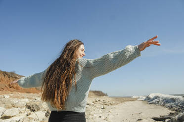 Smiling woman with arms outstretched standing at sunny day - KVBF00069