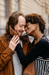 Captured in the heart of the city, this image showcases a young couple intimately engaging, embodying love and affection on the streets, surrounded by the urban environment. - JLPSF31457