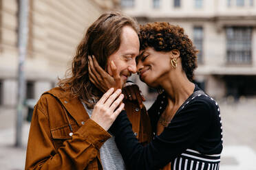 This image captures a tender moment between a young couple, close and embracing on the busy streets, sharing love amidst the urban hustle. - JLPSF31458