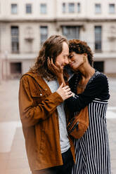 A heartwarming image capturing a young couple in a loving embrace, sharing an intimate moment on a bustling urban street backdrop, showcasing the beauty of young love and connection in an everyday setting. - JLPSF31459