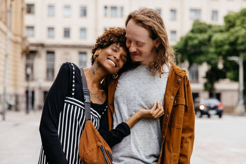 A candid moment of a young couple hugging on a busy city street, portraying urban love, connection, and affection against a backdrop of everyday life. - JLPSF31467