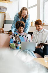 Diverse team working together at a brightly lit co-working space. A casual, collaborative atmosphere with one person typing on a laptop and another reviewing notes. - JLPSF31528