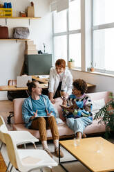 A close-knit team of freelance professionals engage in a collaborative work session in a bright, stylish co-working space. Their interaction signifies productivity and teamwork, set in a casual yet energetic office environment. - JLPSF31536