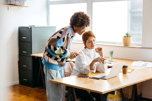 A vibrant image of colleagues working together in a well-lit freelance office setting, demonstrating teamwork and productivity in a co-working environment. The setting exudes creativity and collaborative spirit. - JLPSF31542