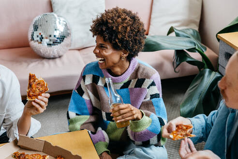 A diverse group of colleagues enjoy a casual meal together in a relaxed freelance office environment, strengthening bonds over delicious pizza slices in a modern co-working space. - JLPSF31611