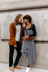 A young couple shares a loving gaze on the urban streets, evoking romance and connection. Their casual attire and joyful expressions suggest comfort and happiness in each other's company, portraying a natural and affectionate relationship. - JLPSF31618