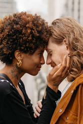 An intimate moment captured as a young, loving couple embrace each other tightly in the bustling streets, showcasing affection and connection amidst urban life. - JLPSF31622