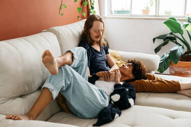 Moment of relaxation captured as a family unwinds together on a comfortable couch, embodying tranquility and the simplicity of enjoying time at home with loved ones in a cozy environment. - JLPSF31627