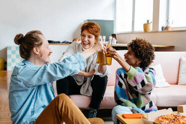 A candid moment in a bright co-working space as freelance colleagues share a toast. The casual office setting radiates a blend of productivity and comfort, reflecting modern work culture and teamwork in a shared workspace. - JLPSF31646