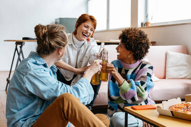 A group of colleagues toasting drinks in a casual freelance office environment, symbolizing success and teamwork in a co-working space. This image captures the spirit of collaboration and celebration. - JLPSF31647