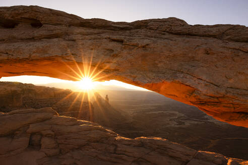 Sunlight envelops the Canyonlands Valley during a summer sunrise, framed by Mesa Arch, Utah, United States of America, North America - RHPLF32483