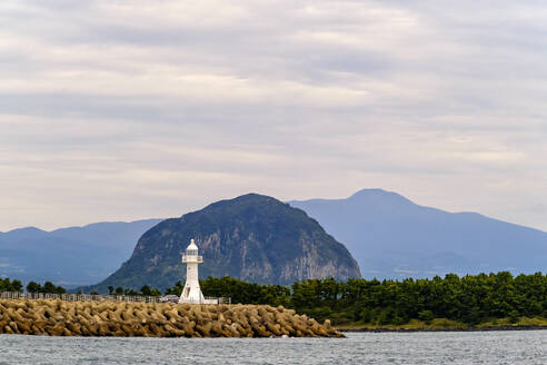 Einer der vielen Leuchttürme der Insel Jeju steht vor dem Berg Sanbangsan und dem Berg Hallasan, einem Schildvulkan, Insel Jeju, Südkorea, Asien - RHPLF33475