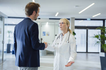 Doctor shaking hands with man in hospital - JOSEF23954