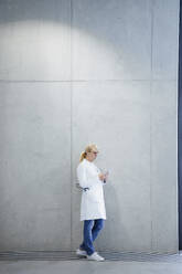 Doctor using smart phone near wall - JOSEF23965