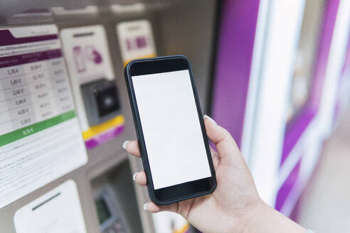 Hand einer Frau, die eine mobile App an einem Fahrkartenautomaten benutzt - PNAF06182