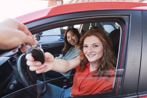 Lächelnde Frau nimmt Autoschlüssel vom Verkäufer entgegen - PNAF06186