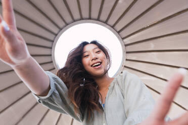 Happy woman with long hair dancing under canopy - PNAF06206