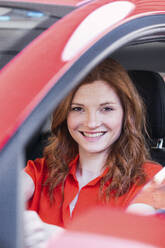 Smiling redhead woman in car - PNAF06222