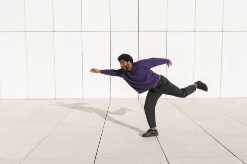 Portugal, young man running against the minimalistic white tile wall - VRAF00480