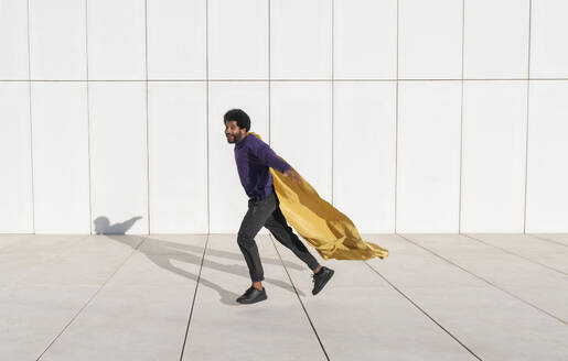 Portugal, young man running against the minimalistic white tile wall - VRAF00483