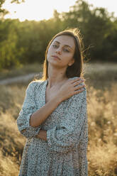 Peaceful woman standing in a field in nature - ALKF01109