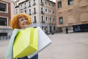 Senior woman with shopping bags on footpath - ALZF00009