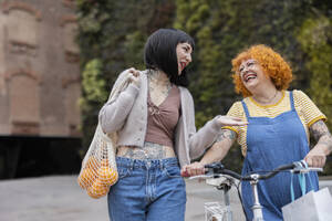 Happy mother and daughter talking to each other on footpath - ALZF00028