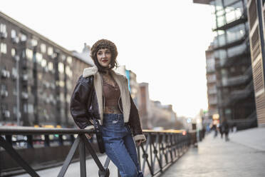 Woman leaning on railing in city - ALZF00045