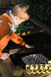 Junge bereitet Erde und Dünger für die Anpflanzung von Kartoffeln im Garten vor - GISF01057