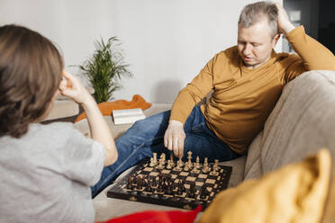 Father and son playing chess on sofa at home - ELMF00146